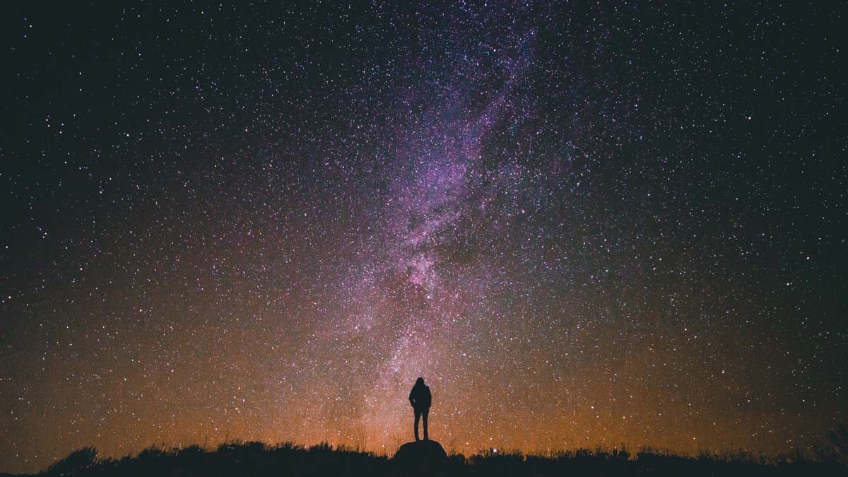 A silhouette of a person looking at the galaxy
