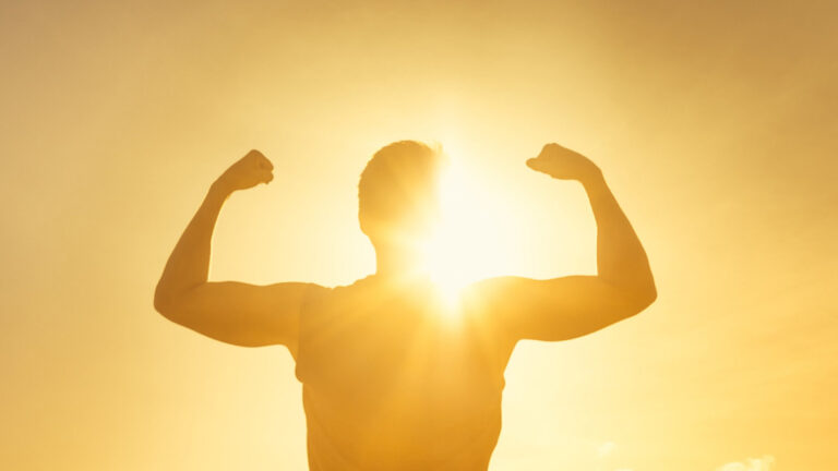 Silhouette of a man flexing his muscle towards the sun