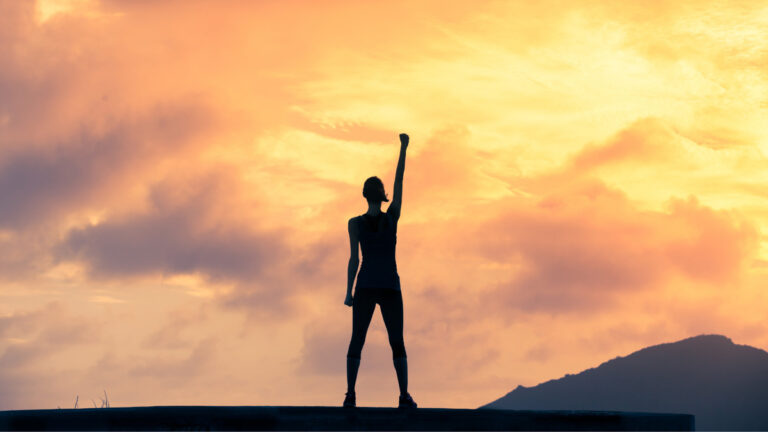 Strong woman with her arm up towards the sky