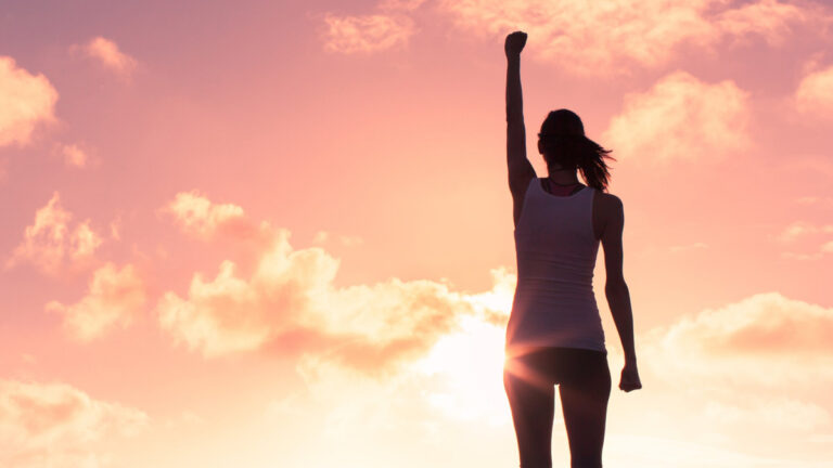 A motivated woman raising her arm in the sky