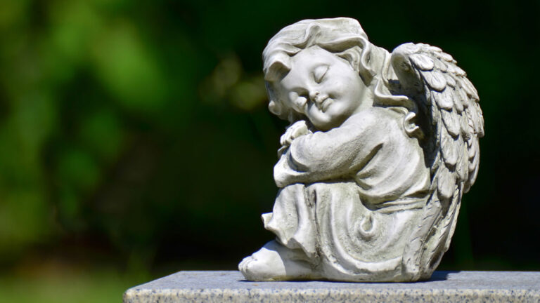 An angel baby statue with wings sitting down.