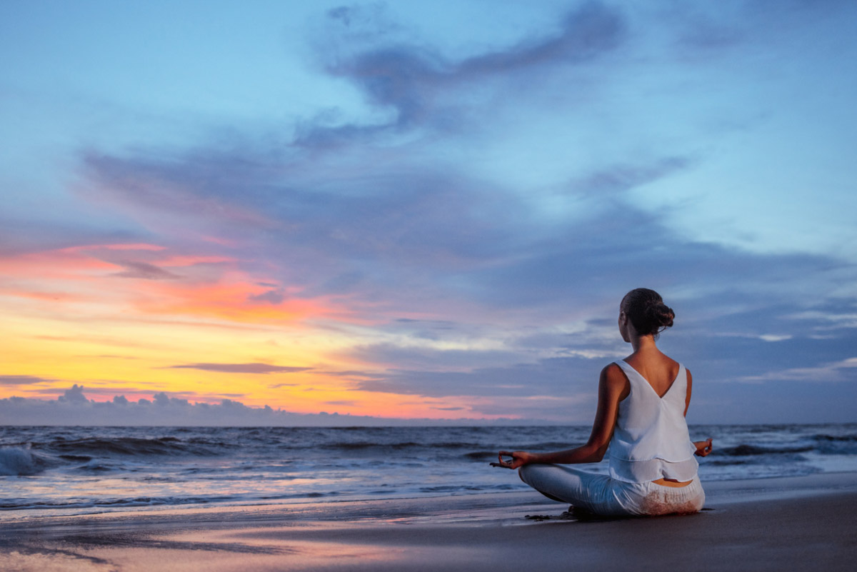 A woman meditating on the beach.