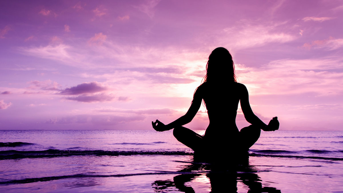 A woman meditating in a mystic purple horizon.