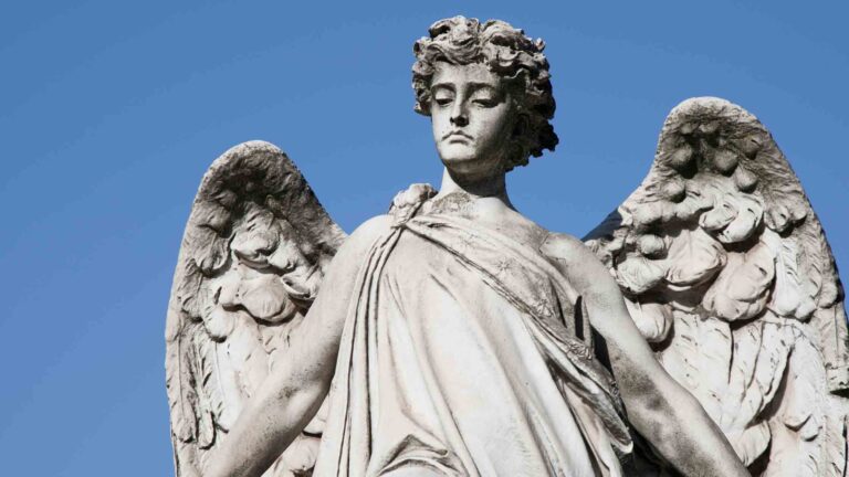 A winged angel statue behind a clear blue sky.