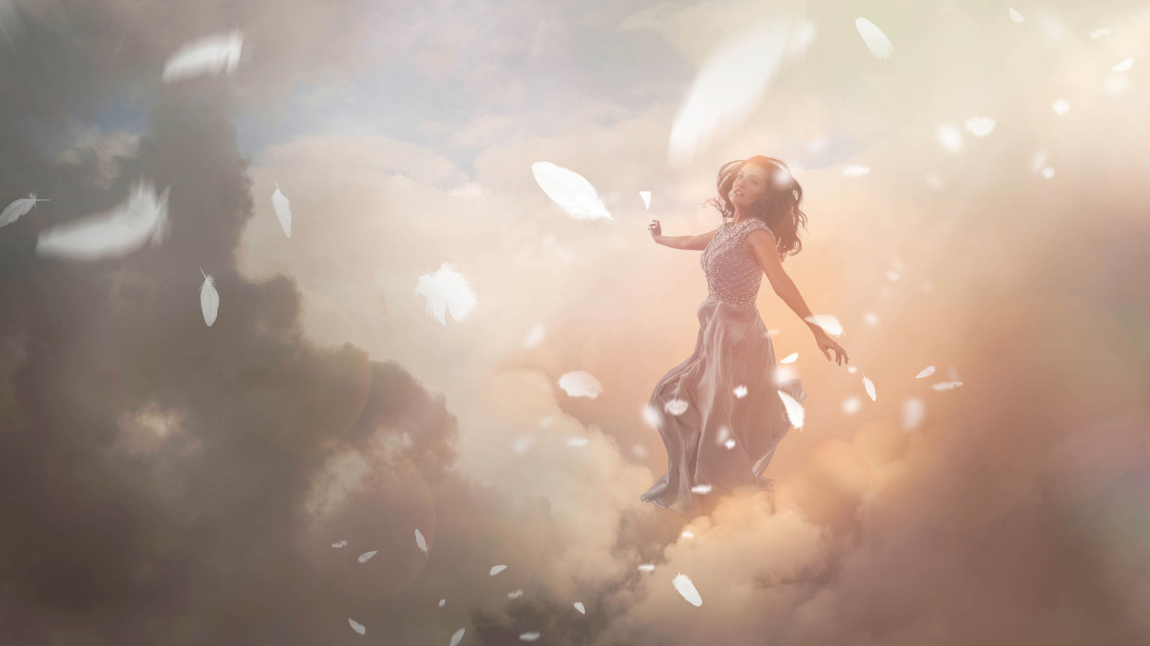 A beautiful woman floating in clouds with feathers falling around her.