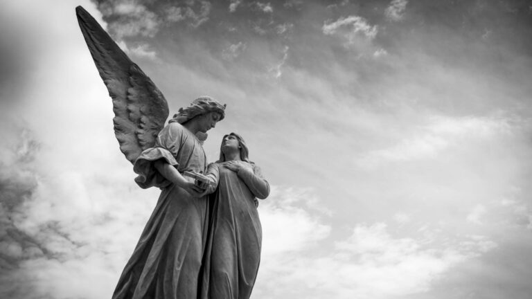 A winged angel statue holding the hand of another.