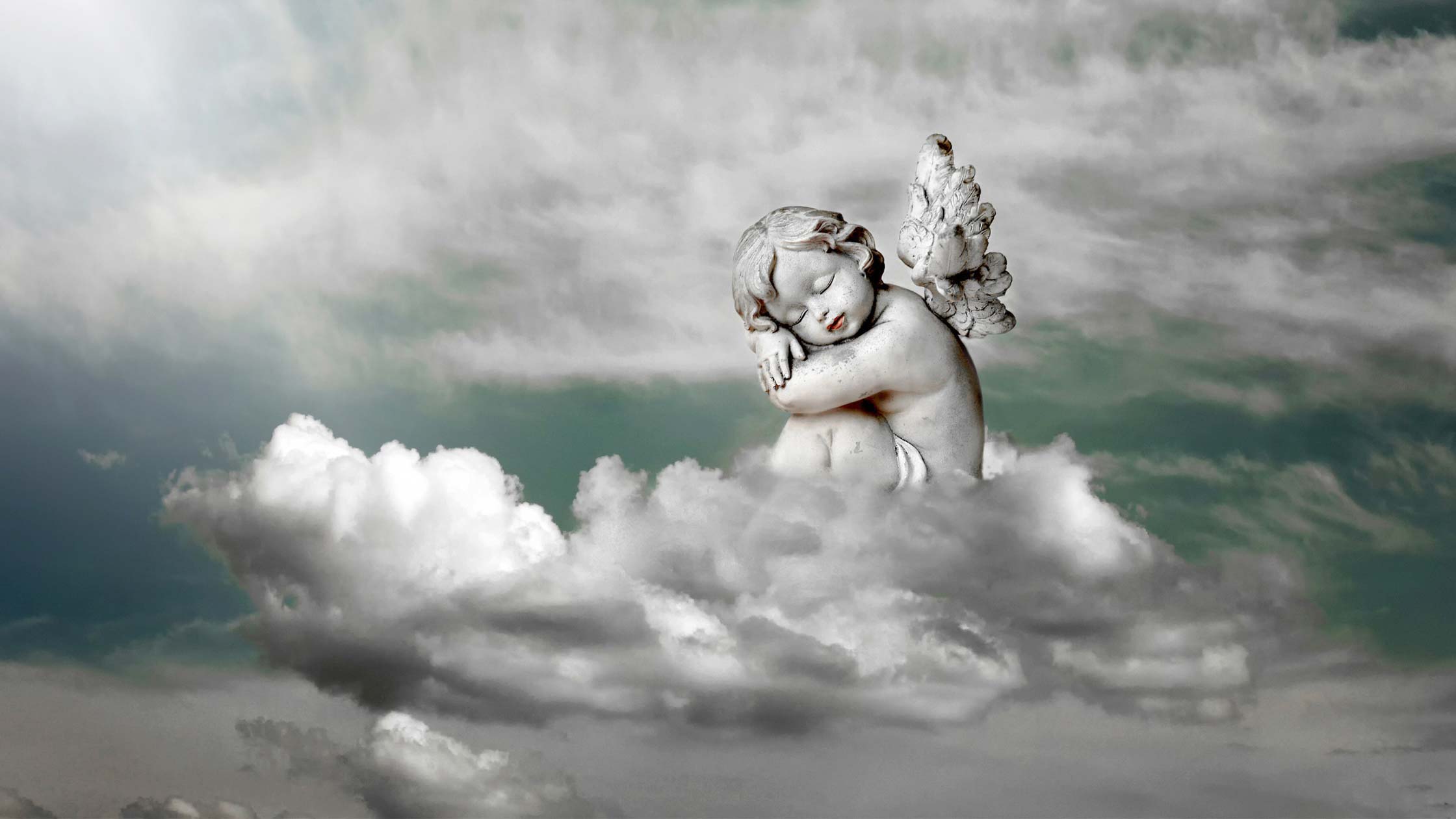 A statue winged baby angel floating on clouds.